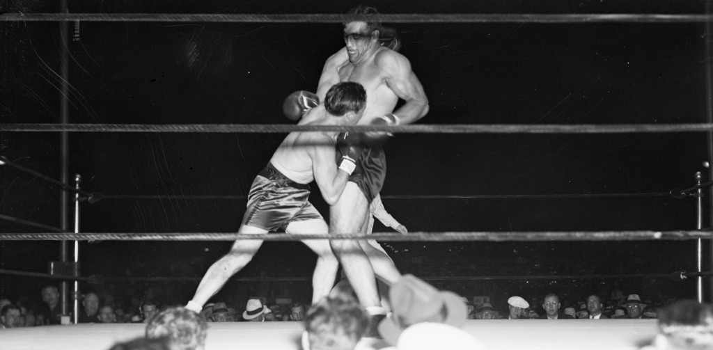 01 Mar 1934, Miami, Florida, USA --- 3/1/1934-Miami, FL- Using his greater height and weight to advantage, Primo Carnera successfully defended his heavyweight championship against Tommy Loughran when he was awarded the decision at the end of 15 rounds. With Carnera towering over him, Loughran is shown here missing a left lead to the champion's head. --- Image by © Bettmann/CORBIS