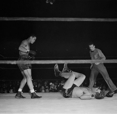 Original caption: New York, New York: Louis Wins In First Over Baer. Joe Louis battered Buddy Baer to the canvas only 2 minutes and 56 seconds after the fight, for Navy relief in the Madison Square garden, Jan. 9, began. Photo shows Baer as he landed on his back on the canvas after a flock of right uppercuts by Louis (Left) had landed him there in final knockout. Referee Frankie Fullam is at right. January 9, 1942 Manhattan, New York, New York, USA