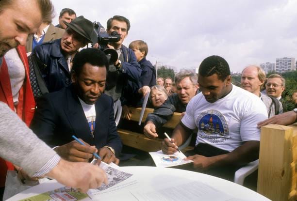 Mike Tyson and Pele signing autographs