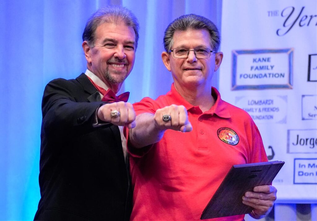 L-R FLBHOF Announcer Bob Alexander with 2020 Inductee referee Emil Lombardi, Jr. showing off their FLBHOF Championship Rings.