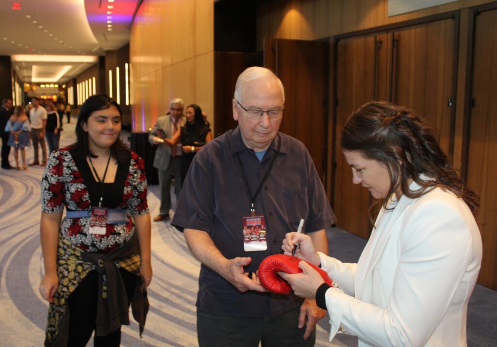 Katie signs a glove for a fan.